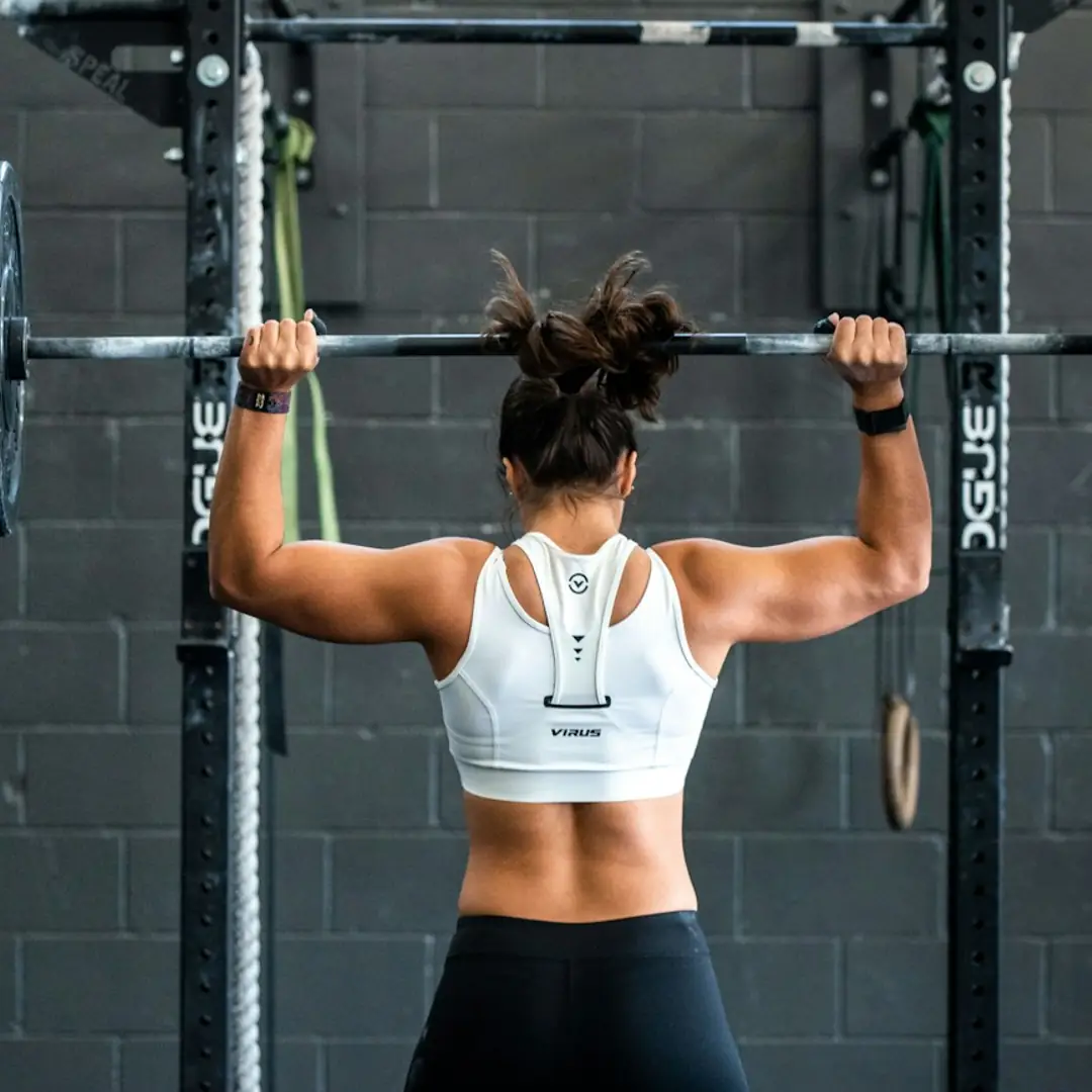 Woman doing barbell work at a squat rack