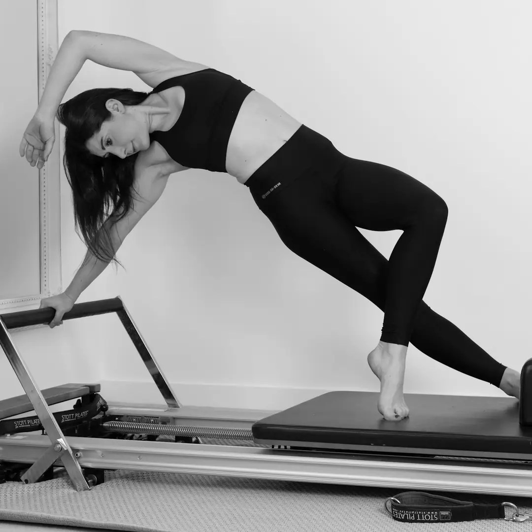 Woman holding a side plank on a Pilates reformer