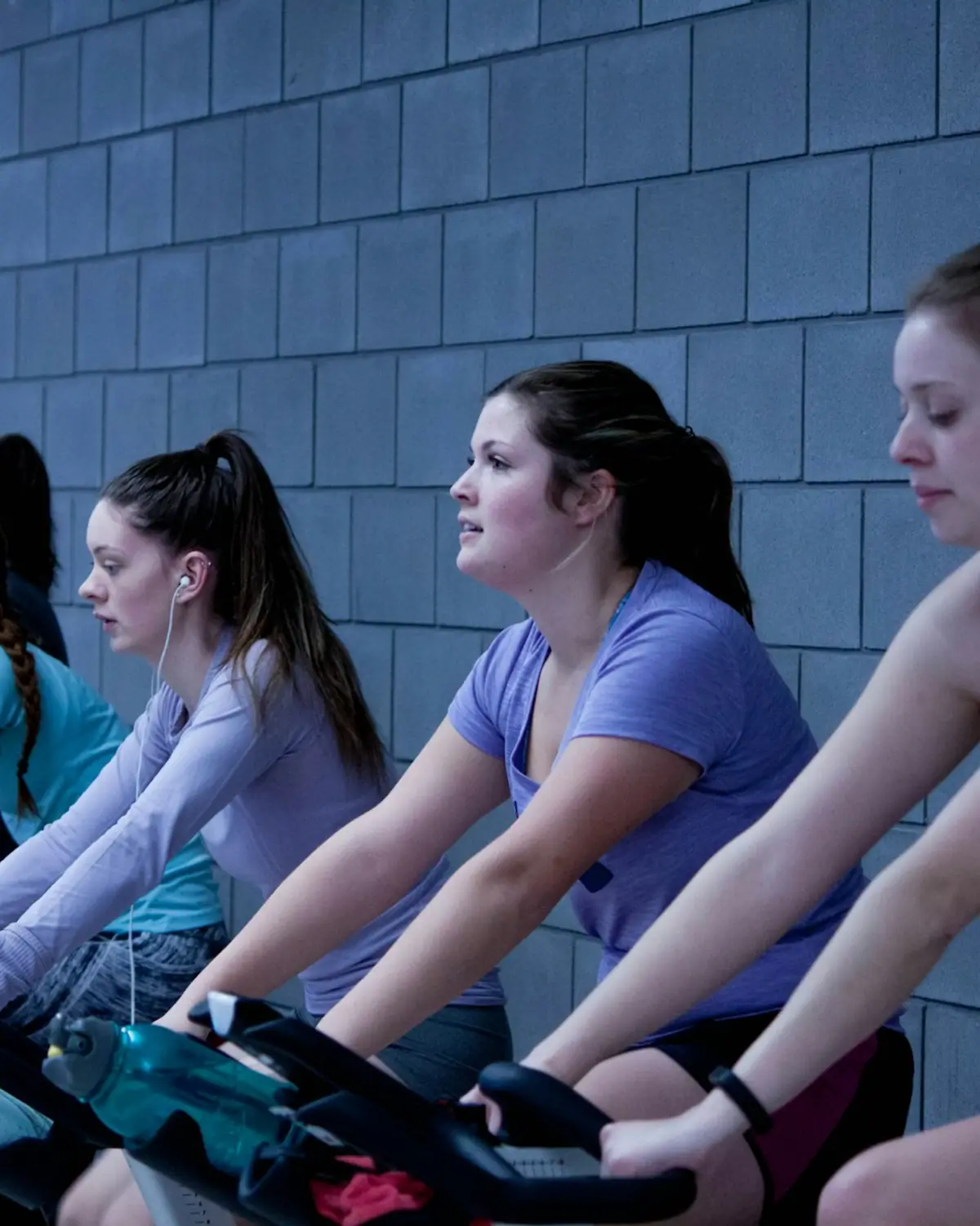Women riding indoor cycling bikes in an energetic class